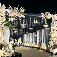 A spectacular entrance for a glamorous evening event. The archway is made of white pampas grass and illuminated by hanging chandeliers and crystal strings.