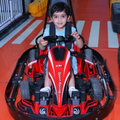 A happy driver gives a wave from his red sport racing go-kart before taking off on the track.