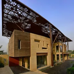 A view of the Tree House's facade, showing the interplay between the solid teakstone walls and the light, perforated canopy above. Carefully placed openings create a dynamic geometry of solid and void.