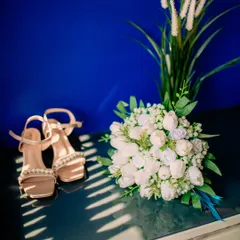 A beautifully styled flat lay of the bride's accessories, including her shoes and bouquet, captured in artistic light and shadow.