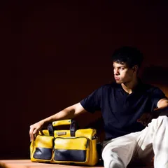 A moody and fashionable shot of a model with Verman Atelier's yellow and black leather bag. The dramatic lighting and relaxed pose create a cool, urban vibe, highlighting the bag as a statement accessory.