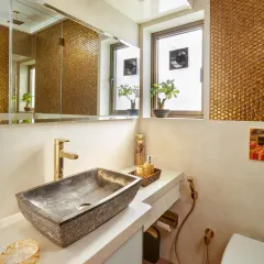 This powder room is all about warmth and texture. The golden penny-round mosaic tiles create a stunning accent wall, perfectly complemented by a natural stone vessel sink and brushed gold fixtures.