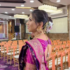A side view showcasing an elegant floral bun on a Maharashtrian bride. The hairstyle is adorned with fresh flowers and traditional accessories, perfectly complementing her saree.