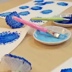 A close-up of the bubble wrap painting process, with different shades of blue paint ready for creating art. We encourage experimentation with colors and materials.
