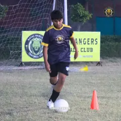 A player practices dribbling around a cone, a fundamental drill to improve close control and agility. We focus on mastering the basics to build a solid technical foundation for every child.