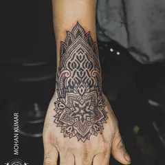 An ornamental mandala tattoo designed to fit the hand and wrist. This style of tattoo is like permanent jewelry, with detailed patterns that flow with the body's shape.