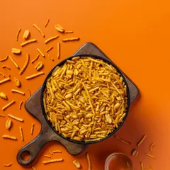 A spicy mixture photographed from above for Sartaj Sweets & Namkeen. The bright orange background complements the warm tones of the snack, creating an energetic product shot.