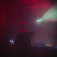 From behind the console, surrounded by red lights and smoke. This is my element, shaping the sound and guiding the energy of the dance floor through the night.