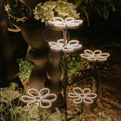 I love incorporating unique lighting elements. These custom-made, whimsical flower-shaped neon lights were placed within the greenery to add a magical, playful glow to the engagement party entrance.