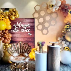 A chic and modern "Mama to Bee" baby shower setup, featuring a stylish peacock chair, a rustic wooden backdrop, and a beautiful balloon arch in warm, earthy tones.