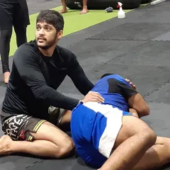 A closer look at the coaching moment, focusing on position and control from the top. Details make all the difference in grappling.