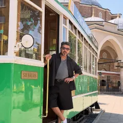 Posing by a vintage tram in Sofia, Bulgaria. My outfit is a study in monochrome, with a black open shirt, grey tee, and black shorts, perfect for a stylish day of exploring.