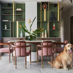 Another view of the pet-friendly dining space in the "Whimsical House." The combination of the green shelving, pink chairs, and marble table creates a playful yet elegant atmosphere.