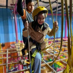 Here's a young adventurer tackling our high ropes course. With a helmet, harness, and a staff member guiding her, she can safely navigate the obstacles and feel a great sense of accomplishment.