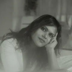 An intimate indoor portrait in black and white. The model's soft smile and relaxed pose, combined with a dreamy, foggy effect, result in a gentle and timeless image.