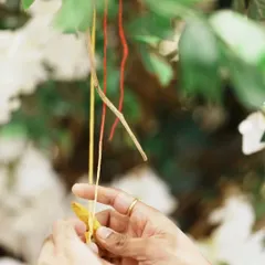 A close-up of a guest tying a thread on the Tree of Blessings. Each knot represents a heartfelt wish, binding the couple in love and community prayer.