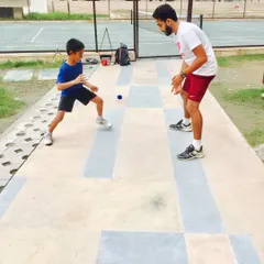 I guide a young athlete through a reaction drill, focusing on his stance and readiness. This type of training is crucial for developing the quick, instinctive movements needed to react to unpredictable shots.