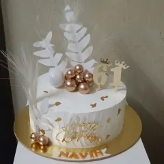 This 61st birthday cake has a modern, artistic feel with white wafer paper leaves, pampas grass accents, and a cluster of gold spheres. It’s a chic design for a stylish celebration.