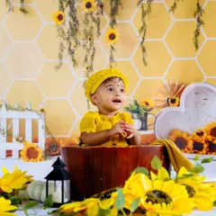 A happy baby enjoying our sunflower and honeycomb studio setup. The warm yellow tones and cheerful props create a wonderfully sunny atmosphere.