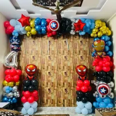 An action-packed Avengers theme birthday for a young superhero fan. The setup includes a full balloon frame with character foils of Iron Man, Captain America, and Spider-Man, set against a wood-paneled wall for a dynamic look.