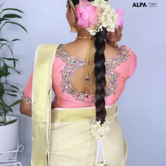 The back view of a classic South Indian bridal hairstyle, featuring a thick braid decorated with fresh lotus and jasmine flowers.