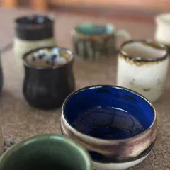 A collection of finished pots from my beginner wheel throwing course. The variety of shapes and glazes is a testament to their hard work and creativity.