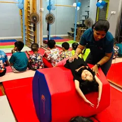 Safety and proper technique are at the core of our teaching. Here, an instructor provides hands-on support to a young gymnast learning a backbend over a soft octagonal tumbler, ensuring she builds flexibility and strength correctly.
