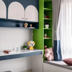 This kid's room features a custom study desk with blue and white arched cabinets and a vibrant green bookshelf. The cozy window seat is perfect for reading.