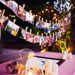 A charming outdoor photo garland for an evening celebration. I hang your pictures using clothespins on a string of fairy lights, creating a warm and personal atmosphere.