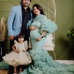 Here is the complete family portrait from the mint green gown session. The parents are posing with their adorable daughter, who is wearing a matching ruffled dress. It’s a perfect shot to announce you’re growing your family.