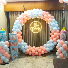 A classic 'gender reveal' style baby shower decoration for the home. It features a full balloon ring in pastel pink and blue, an 'Oh Baby' neon sign, and 'BABY' blocks on either side.