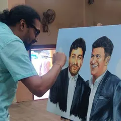 Here I am, adding the final touches to the double portrait of Dr. Rajkumar and Puneeth Rajkumar. Working on a large canvas with acrylics allows for building up layers to create realistic skin tones and expressions.