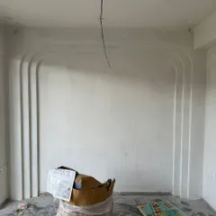 Before: The initial state of a bedroom wall in 'Project Lily', prepped for custom paneling and finishing.