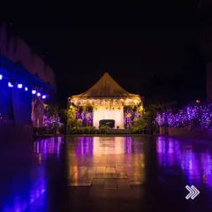 The Terrace Garden transforms into a magical space at night. The reflection on the wet floor doubles the beauty of the purple ambient lighting and the charming tented stage.