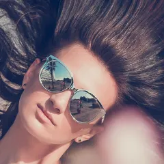 A creative and modern approach to sunglass photography. Using the lenses as a reflective surface to show a palm tree adds a narrative element, making it a perfect shot for a fashion magazine or an Instagram campaign.