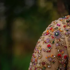 This is where the magic lies. A close up of a hand embroidered blouse sleeve, showcasing intricate, multi colored floral zardozi and beadwork on sheer fabric. Each stitch is a testament to the hours of artistry poured into my creations.