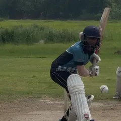 A young batswoman playing a confident front foot shot during a match. Her focus and technique are excellent.