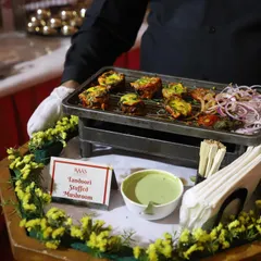 A close-up of my Tandoori Stuffed Mushrooms, a crowd-pleasing appetizer. The mushrooms are marinated in spices, stuffed with a savoury filling, and grilled to perfection, served hot on a portable grill tray.