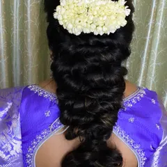 A lovely pull-through braid adorned with a simple jasmine gajra. This hairstyle offers a modern texture while maintaining a touch of traditional elegance.