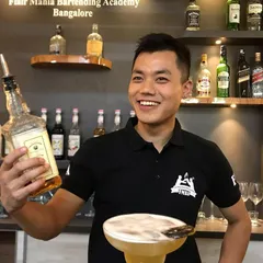 A happy bartender from our Bangalore academy, showcasing his latest cocktail creation with a smile.