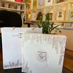 This premium invitation set includes a beautiful box-style card with a matching carry bag. The design features a delicate wisteria flower print and a custom monogram, creating a cohesive and elegant presentation.