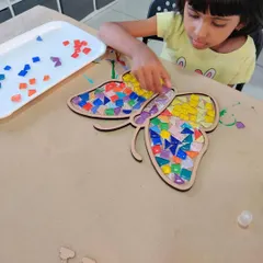Look at the focus and creativity! This is what it's all about, a hands-on activity where kids can get lost in making something beautiful, like this colorful butterfly mosaic.