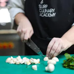 Mastering knife skills is the first step for any aspiring chef. Here, a student practices their dicing technique on mushrooms under our guidance.
