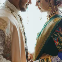An intimate portrait of a Maharashtrian couple, their foreheads touching, showcasing the delicate details of the mundavalya and traditional jewelry.