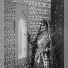 A timeless black and white portrait of the bride in her full wedding attire, looking out a window, creating a classic and elegant image.
