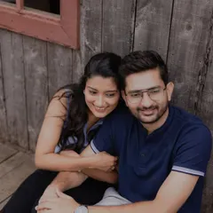 A cozy and relaxed moment against a rustic wooden wall. This candid shot captures the easy comfort and affection of a couple simply enjoying being together.