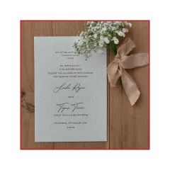 A closer look at the blind letterpress technique on this invitation. The floral pattern is pressed into the thick cotton paper without ink, creating a subtle, elegant texture that you can feel. The design is finished with a hand-tied silk ribbon.