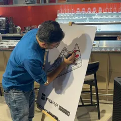 An event attendee participates in our collaborative art activity, adding his own drawing to the large sneaker canvas. This interactive element is always a huge hit with guests of all ages.