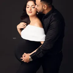 The perfect blend of classic and modern. This couple's maternity portrait showcases an elegant off-the-shoulder black and white gown, with the father-to-be's tender embrace adding a layer of warmth.