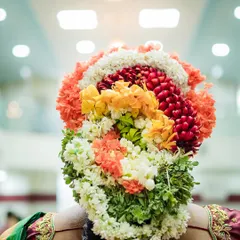 The intricate and colorful floral arrangement in the bride's hair, a beautiful tradition in South Indian weddings that we love to photograph.